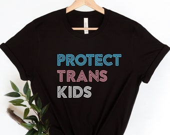 May include: Black t-shirt with the text "PROTECT TRANS KIDS" in blue, pink, and white outlined letters.