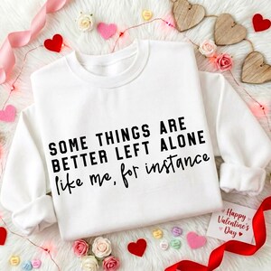 May include: White sweatshirt with the text "SOME THINGS ARE BETTER LEFT ALONE like me, for instance." The image is decorated with red hearts, pink hearts, and a "Happy Valentine's Day" card.