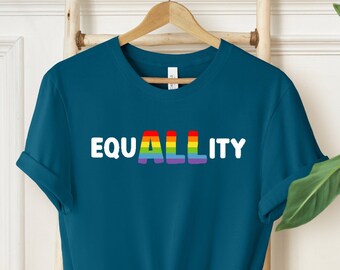 May include: A teal blue t-shirt with the word "EQUALITY" printed in white letters. The word "ALL" is in rainbow colors.