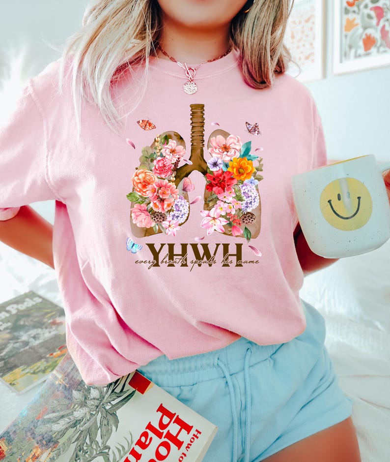 May include: Pink t-shirt with a floral design of lungs and the text "YHWY every breath speaks his name".
