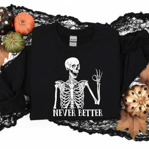 May include: Black sweatshirt with a white skeleton graphic giving a thumbs up and the text "Never Better".