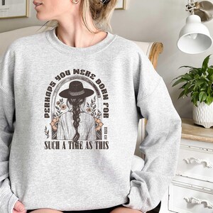 May include: Gray sweatshirt with a graphic print of a woman wearing a cowboy hat and the text "Perhaps you were born for such a time as this".