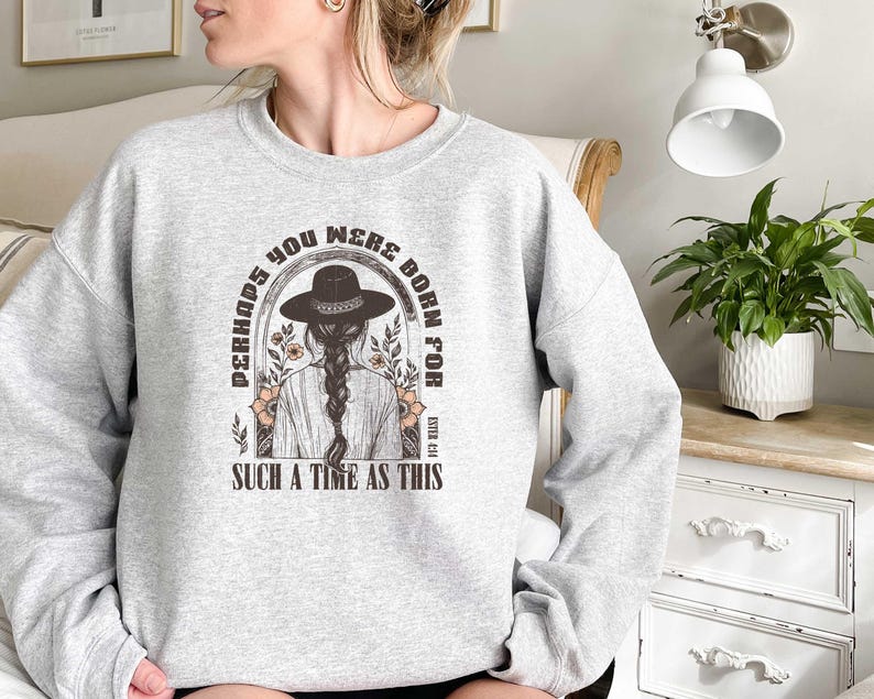 May include: Gray sweatshirt with a graphic print of a woman wearing a cowboy hat and the text "Perhaps you were born for such a time as this".