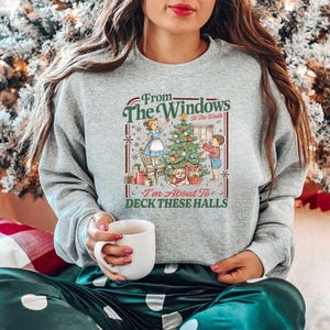 May include: A gray sweatshirt with a festive Christmas graphic. The graphic features a decorated Christmas tree, a woman, a child, and the text "From The Windows To All The Walls I'm About To Deck These Halls."