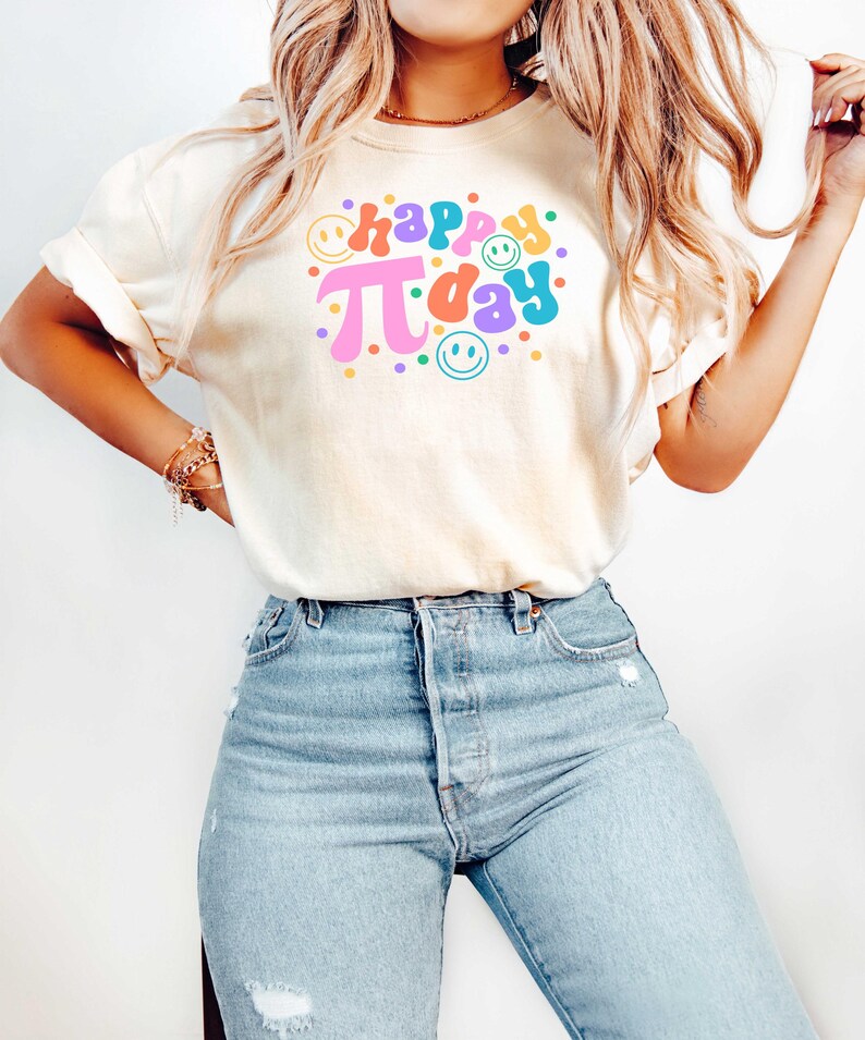 May include: A white t-shirt with the text "happy pi day" in colourful retro font with smiley faces and colourful dots.