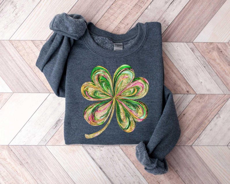 May include: A dark gray sweatshirt with a green, gold, and pink four-leaf clover design.