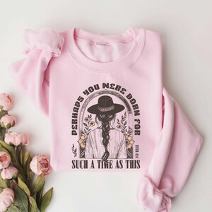 May include: Pink sweatshirt with a graphic print of a woman wearing a hat and the text "Perhaps you were born for such a time as this" with the Bible verse Esther 4:14.