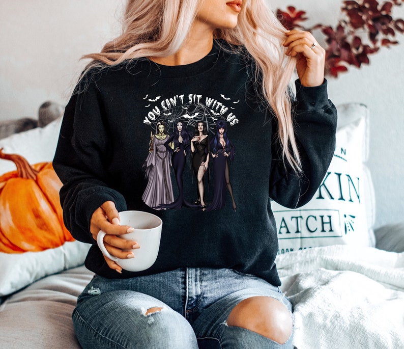 May include: Black sweatshirt with a graphic print of three women in black dresses and the text "You can't sit with us".