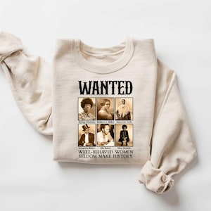 K&ouml;nnte beinhalten: Ein beiger Pullover mit einem schwarzen Grafikdruck, der "WANTED" sagt und eine Collage aus Schwarzwei&szlig;fotos von Frauen zeigt. Der Text unter den Fotos lautet "WELL-BEHAVED WOMEN SELDOM MAKE HISTORY."