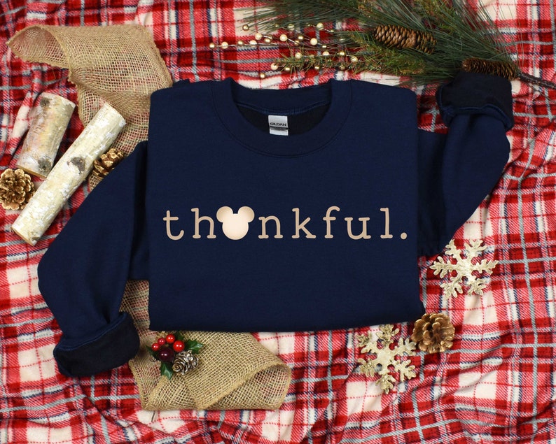 May include: A navy blue sweatshirt with a gold Mickey Mouse head and the word "thankful" in gold lettering.