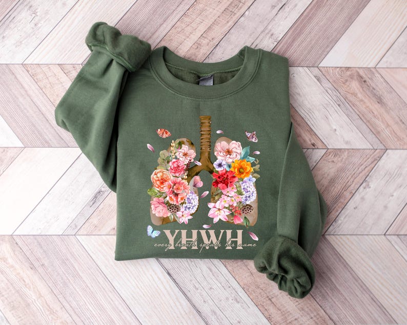 May include: A green sweatshirt with a floral design of lungs and the text "YHW", which stands for "every breath you take, breathe life into the home".