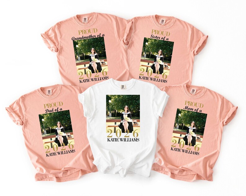 May include: A collection of peach and white t-shirts featuring a graduation photo and the text "PROUD Grandmother of a", "PROUD Dad of a", "PROUD Sister of a", and "PROUD Mom of a". Each shirt includes the graduate's name and the year 2026.