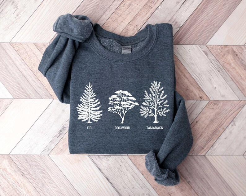 Pu&ograve; includere: Una felpa grigia scura con una grafica bianca di tre alberi. Gli alberi sono etichettati "Fir", "Dogwood" e "Tamarack".