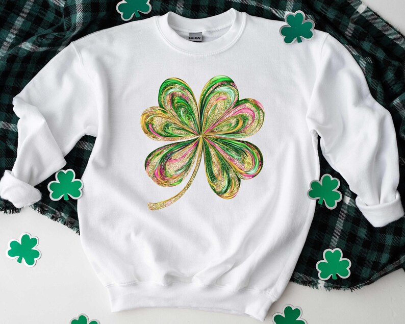 May include: White sweatshirt with a green, gold, and pink four-leaf clover design. The clover is stylized with a swirling, marbled pattern.