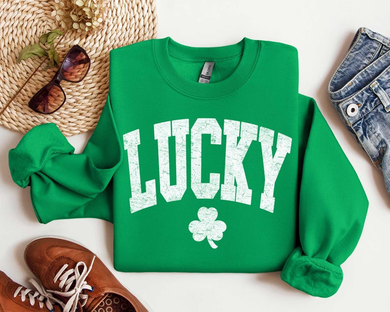 Peut inclure: Sweat-shirt vert avec un graphisme blanc de style vintage qui dit "LUCKY" avec un tr&egrave;fle &agrave; quatre feuilles en dessous.