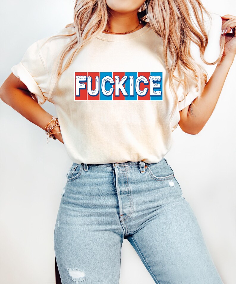 以下が含まれることがあります： 「FUCKICE」の文字が赤、白、青の長方形のデザインでプリントされたクリーム色のTシャツ。明るいブルーデニムのジーンズと合わせています。