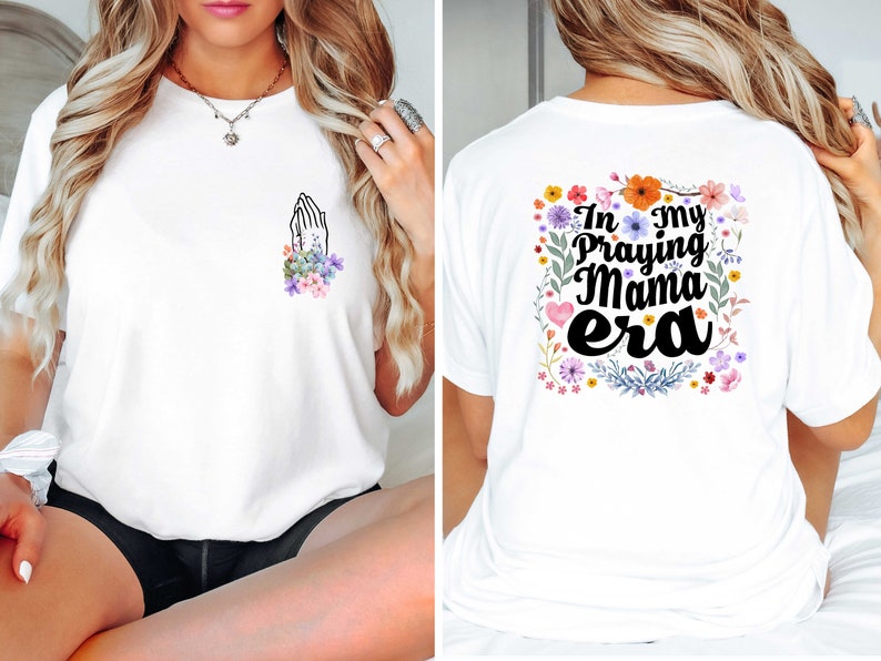 May include: White t-shirt with a floral design and the text "In my praying mama era" on the back. The front of the shirt has a small floral design with a praying hands graphic.