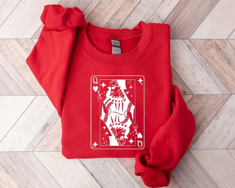 May include: Red sweatshirt with a white graphic of a queen of hearts playing card. The queen is wearing sunglasses and a crown.