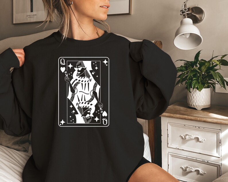 May include: Black sweatshirt with a white graphic of a queen of hearts playing card. The queen is wearing sunglasses and holding a flower.