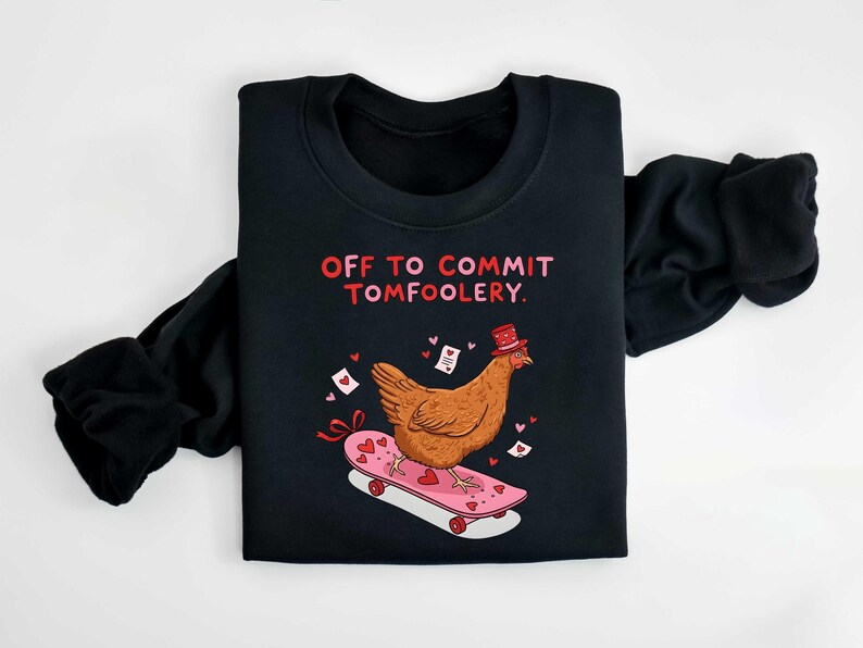 K&ouml;nnte beinhalten: Schwarzes Sweatshirt mit dem Text "OFF TO COMMIT TOMFOOLERY". Ein Cartoon-Huhn mit Zylinder f&auml;hrt auf einem rosa Skateboard mit Herzdekorationen. Das Design beinhaltet Herzen und Liebesbriefe.