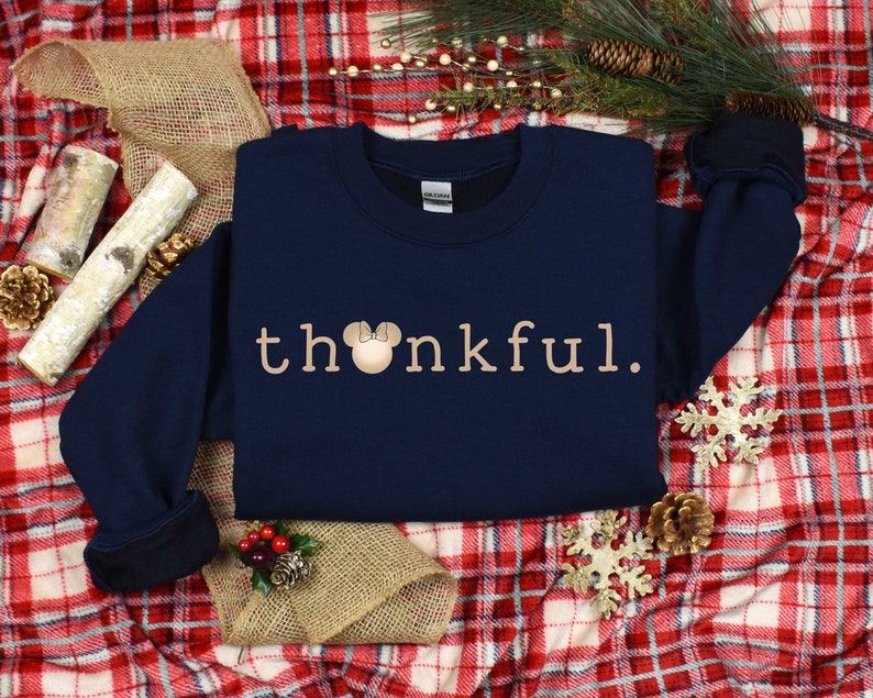 May include: Navy blue sweatshirt with the text "thankful" in beige with a beige Mickey Mouse head with a red bow.