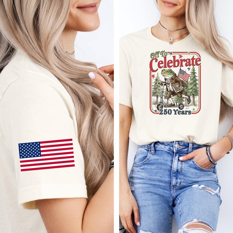 May include: Cream-colored t-shirt with an American flag on the sleeve. The front features a graphic of a frog riding a scooter with the text "Off to Celebrate 250 Years."