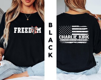 May include: Black t-shirt with the word "FREEDOM" in white block letters and a red, white, and blue bow graphic. The back of the shirt features a distressed American flag design with the name "CHARLIE KIRK" in white.
