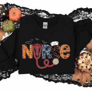Pu&ograve; includere: Felpa nera con una grafica "NURSE" a tema Halloween. Le lettere sono composte da varie icone di Halloween, tra cui pipistrelli, fantasmi, zucche e mais caramellato. Un stetoscopio rosso &egrave; incluso nel design.