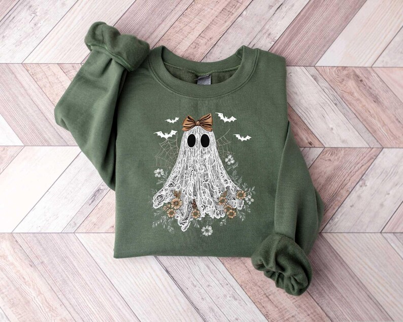 Peut inclure: Un sweat-shirt vert avec un fant&ocirc;me blanc portant un n&oelig;ud brun. Le fant&ocirc;me est entour&eacute; de fleurs et de chauves-souris.