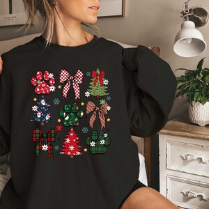 May include: Black sweatshirt with a Christmas-themed design featuring paw prints, bows, and Christmas trees. The design is in red, green, and white.