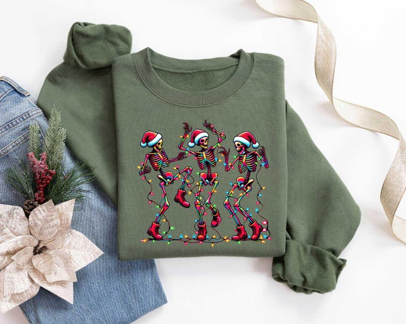May include: Green Christmas sweater with a graphic of three skeletons wearing Santa hats and dancing with Christmas lights.