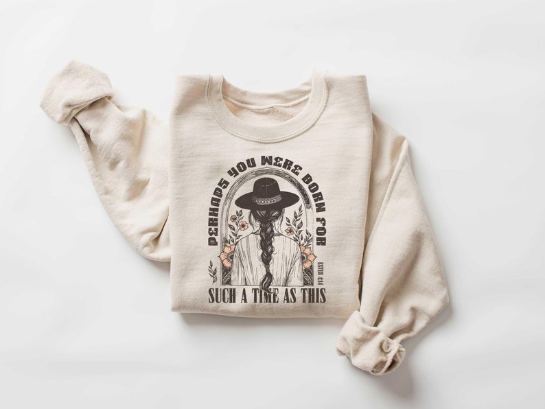 May include: A beige sweatshirt with a graphic print of a woman wearing a cowboy hat and the text "Perhaps you were born for such a time as this".