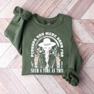 May include: Green sweatshirt with a white graphic print of a woman wearing a hat and the text "Perhaps you were born for such a time as this" and the reference "Esther 4:14".