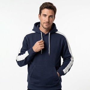 Puede incluir: Sudadera con capucha azul marino con rayas blancas en las mangas. La sudadera con capucha tiene una capucha con cordón y un bolsillo delantero. El modelo lleva la sudadera con capucha. La sudadera con capucha está hecha de un material suave y cómodo.