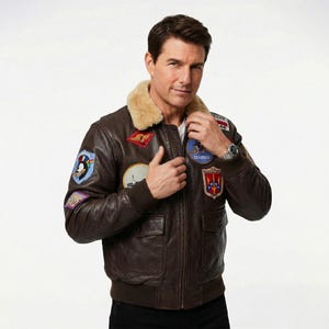 May include: A brown leather bomber jacket with various patches, a tan shearling collar, and ribbed cuffs and hem. The jacket features two front pockets and a zip closure. The patches display military insignia and text. The jacket is worn by a person.