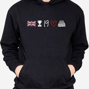 May include: Black hoodie with a white graphic of a British flag, a trophy, the number 19, a red heart, and a brick pattern.