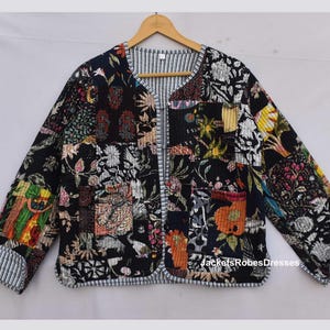 May include: A black quilted jacket with a patchwork design featuring floral and geometric patterns in various colors. The jacket has a striped trim and long sleeves. The text "JacketsRobesDresses" is visible on the lower right side.
