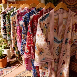 May include: A clothing rack displays a variety of patterned robes in various colors, including pink, blue, red, and green. The robes have floral and paisley designs. The text "JacketsRobesDresses" is visible at the bottom of the image.