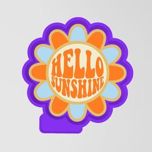 Puede incluir: Un cortador de galletas con forma de flor de color morado con un centro amarillo y el texto "HELLO SUNSHINE" en letras naranjas.
