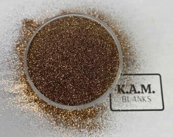 Puede incluir: Primer plano de un pequeño recipiente lleno de brillantina de cobre fina y brillante. La brillantina está suelta y tiene un brillo metálico.