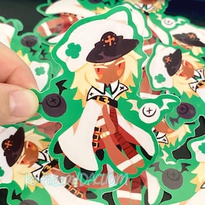 May include: A sticker featuring a cartoon character with blonde hair, a dark hat, and a white coat. The character has brown skin and is set against a green background with a clover-like design. The sticker has a unique shape and is held by a hand.