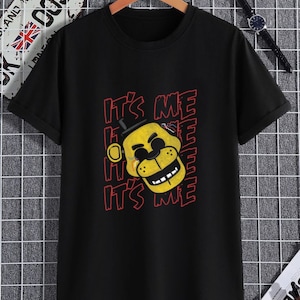 Puede incluir: Camiseta negra con un personaje de dibujos animados amarillo que lleva un sombrero de copa y el texto "It's Me" repetido en rojo.