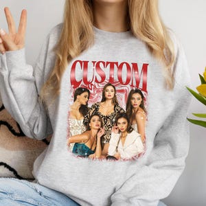 May include: Gray sweatshirt with a red "CUSTOM" graphic featuring five women in a colorful, abstract design.
