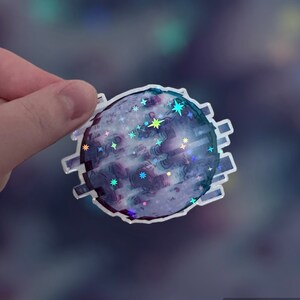 Może przedstawiać: Holograficzna naklejka z księżycem o błyszczącym, tęczowym wykończeniu. Księżyc jest otoczony błyszczącą, tęczową ramką z efektem pikselowym. Księżyc jest otoczony małymi, błyszczącymi gwiazdami.