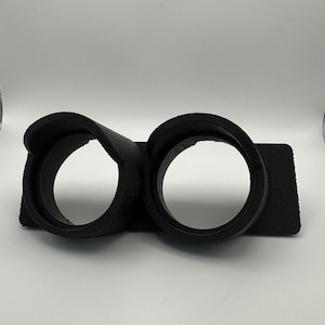 May include: Black double gauge pod with two round openings for gauges. The pod is made of a soft, textured material.
