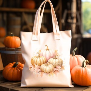May include: A pink canvas tote bag with a design of four white and cream pumpkins with fall leaves. The pumpkins are arranged in a cluster with the largest pumpkin in the center.