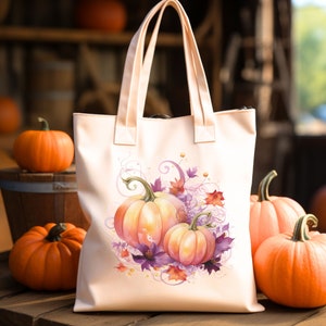 May include: A pink canvas tote bag with a design of three orange pumpkins with purple flowers and leaves. The pumpkins are arranged in a cluster with the largest pumpkin in the back and the two smaller pumpkins in front. The design is surrounded by a swirl of pink and purple.