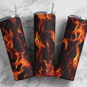 May include: Three stainless steel tumblers with a black and orange flame design. The tumblers have lids and straws.