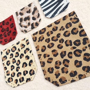 Op de afbeelding: Een assortiment leren patches met dierenprints. De patches bevatten rode, bruine en beige luipaardprints, een zebraprint en een bruine luipaardprint. Elke patch heeft een unieke vorm en is bedoeld voor knutselen of versiering.