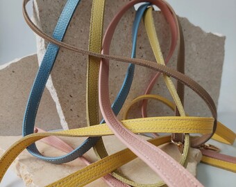 May include: A close-up of five leather straps in different colors, including blue, yellow, brown, and pink. The straps are woven together and appear to be handmade.
